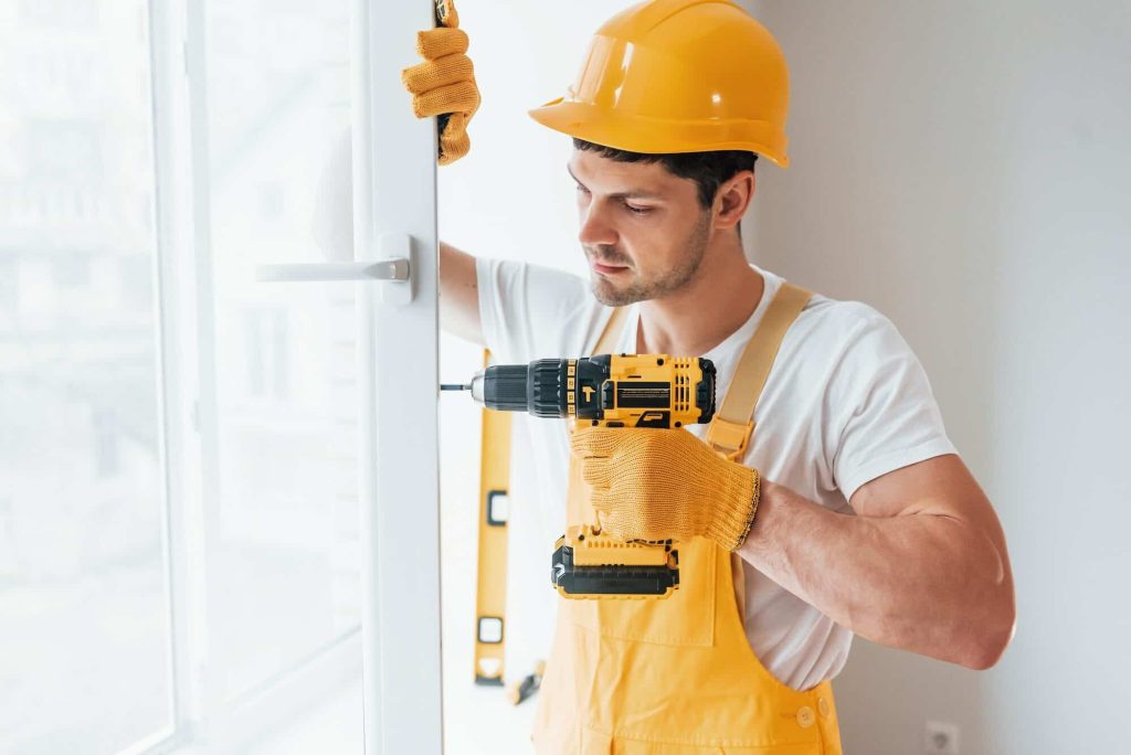 handyman in yellow uniform installs new window e1663969295597